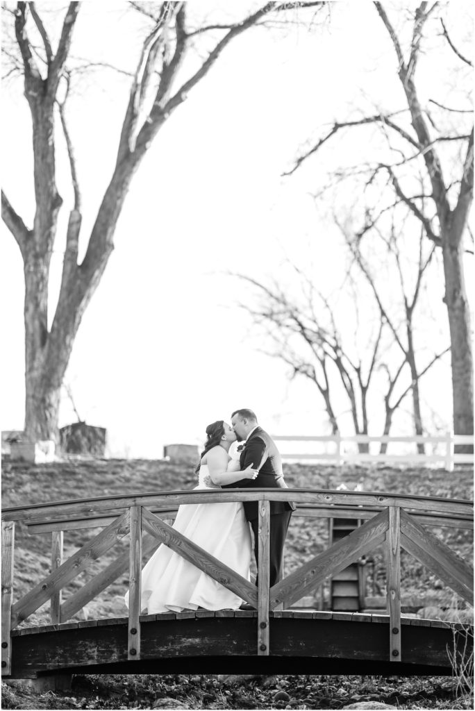 Bride and groom kissing on bridge at Camelot Ranch