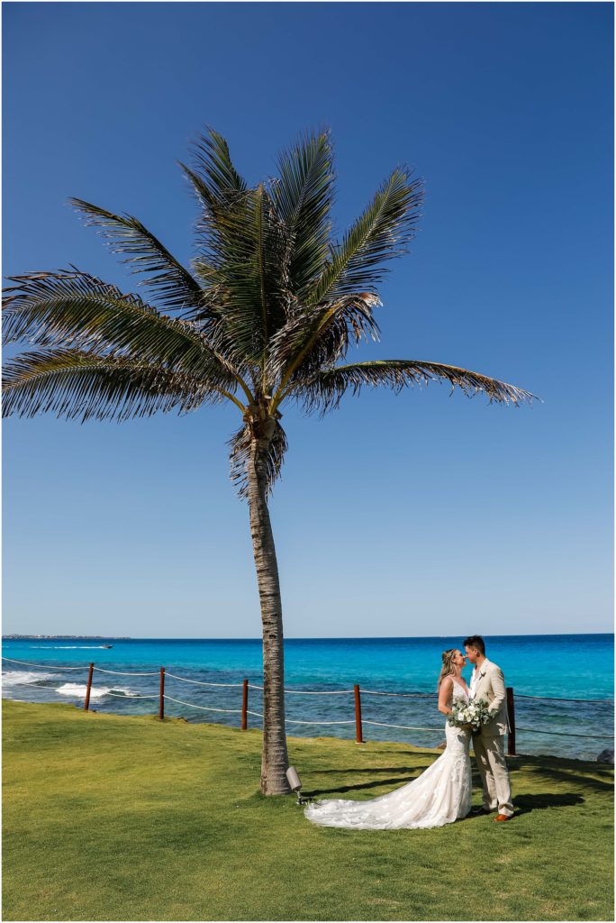 Cancun Destination Wedding Bride and Groom under a palm tree by the ocean