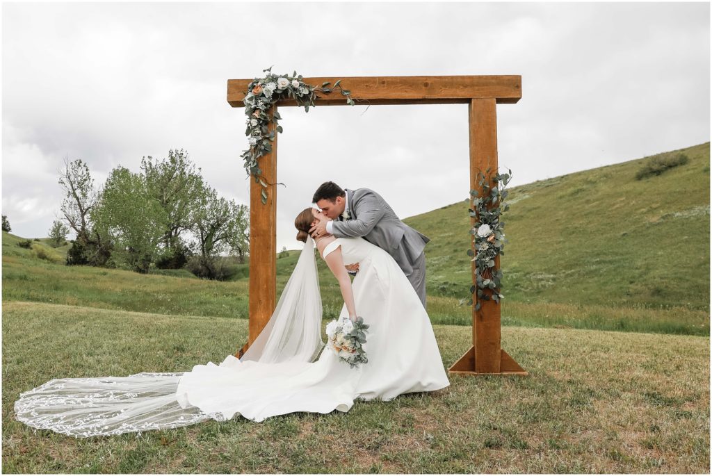 Rainy Spring Wedding Bride and Groom kissing under a wooden arbor