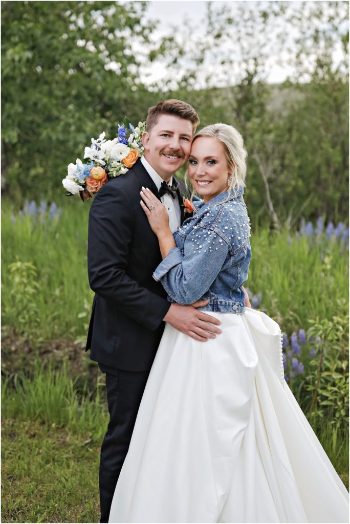 Bride and groom in a grassy field with wildflowers at Venue 406 Wedding