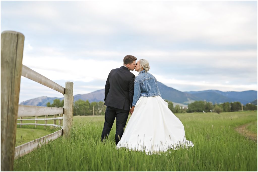 Bride and groom kissing in a grassy field at Venue 406 Wedding